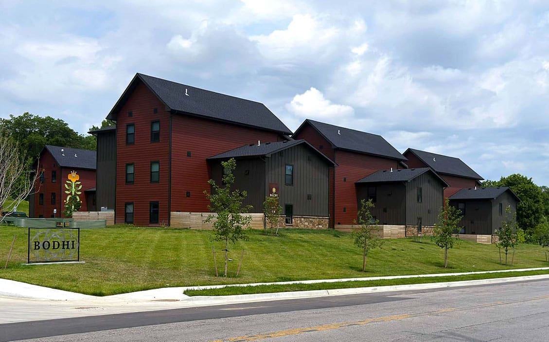 BODHI building complex with red and gray barn-style buildings on a grassy hill