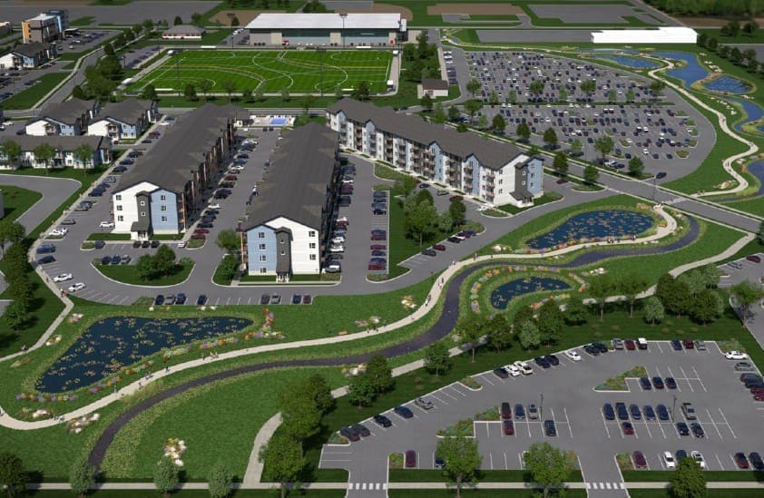 Aerial rendering of an apartment complex with parking lots, sports fields, and landscaped ponds